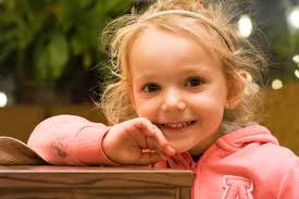 Cute little girl with her hand on a table smiling